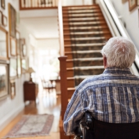 an elderly man in a wheelchair at the bottom of a staircase