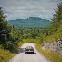 a car on a highway facing mountains and forests