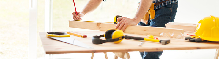 man measuring and cutting wood