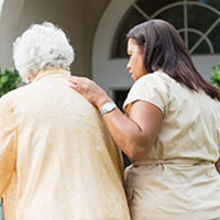 older woman walking with the help of a nurse