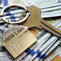 house key with usda loan written on it on top of dollar bills
