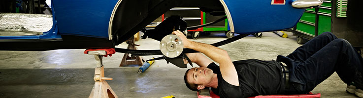 auto mechanic checking shock absorber of vehicle