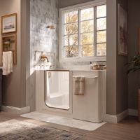 a white walk-in bathtub set in a neutral colored bathroom softly lit by naturally sunlight from a large window