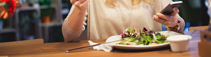 woman eating food while on phone