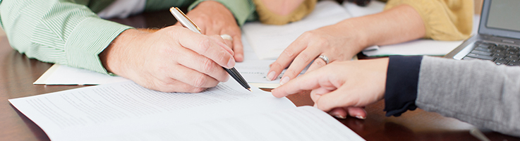couple looking over paperwork before signing while woman points to paperwork