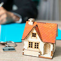 miniature house and keys with banker signing documents