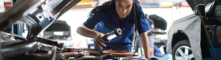 woman mechanic looking under hood of car