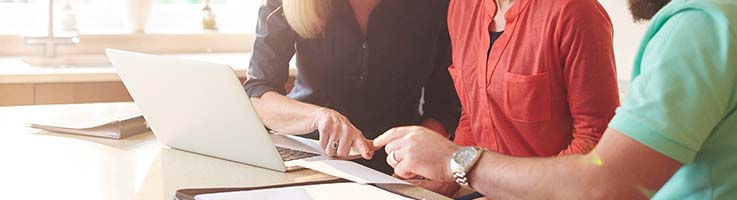 couple looking at paperwork and computer with woman