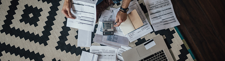 man looking over a lot of bills with calculator and computer