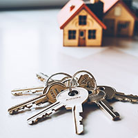house keys in front of miniature model house