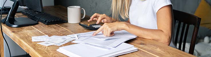 woman pointing at paper typing on calculator