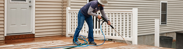 woman power-washing deck