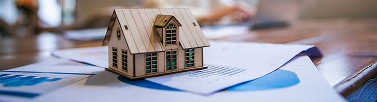 wooden model home on paperwork