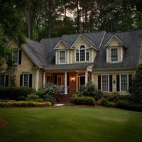 a two-story house with a light yellow exterior, white trim, and a dark gray roof