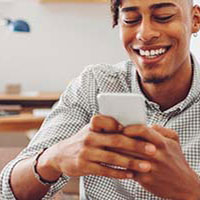 young man smiling while typing on phone