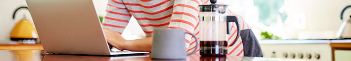 Girl on laptop next to coffee press