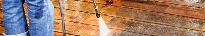 Person pressure washing a deck