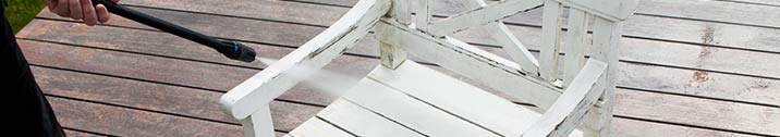 Person pressure washing patio furniture