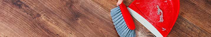Red dustpan and broom on wood floor
