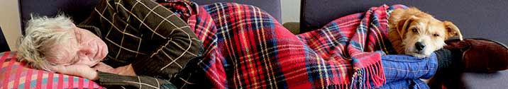 Senior man sleeping on couch with dog