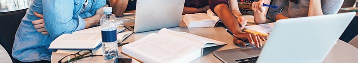 Students at table with books and laptop