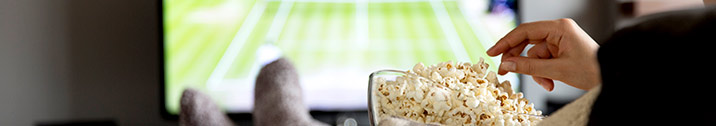 Person watching TV and eating popcorn