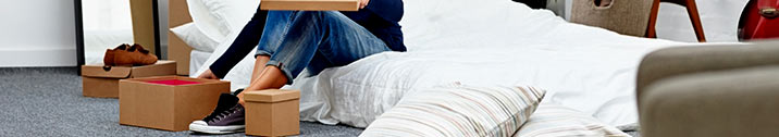 Woman sitting on bed with boxes