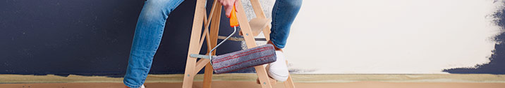 Woman sitting on ladder with paint roller