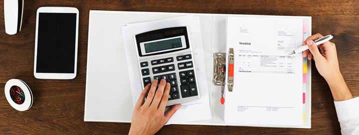Person calculating utility bill and writing in notebook
