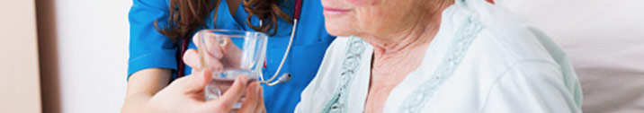 Nurse helping senior woman drink water