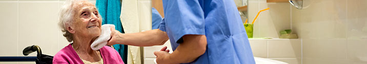 Nurse washing senior patient's face